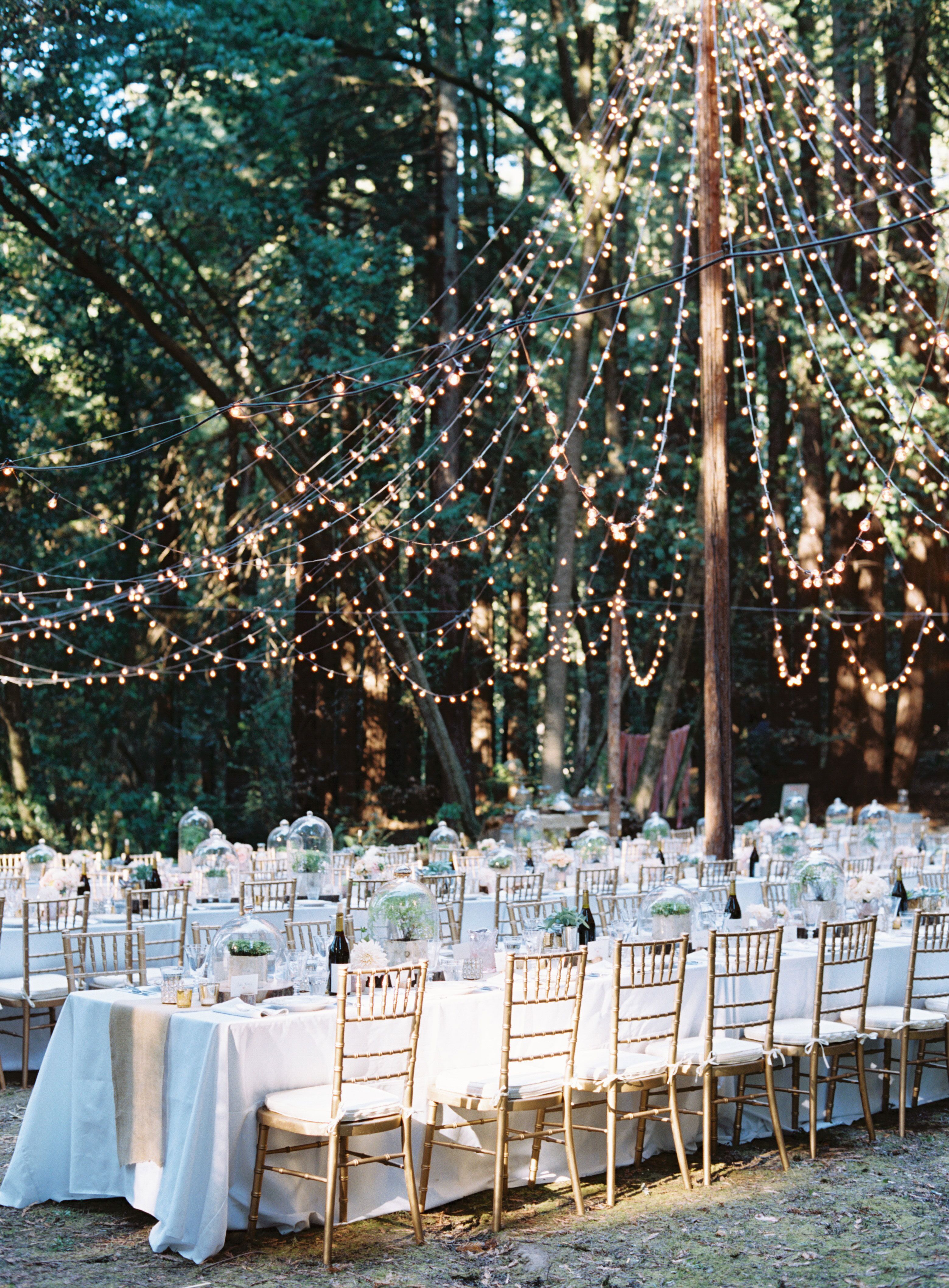 Rustic outdoor string lights over reception tables