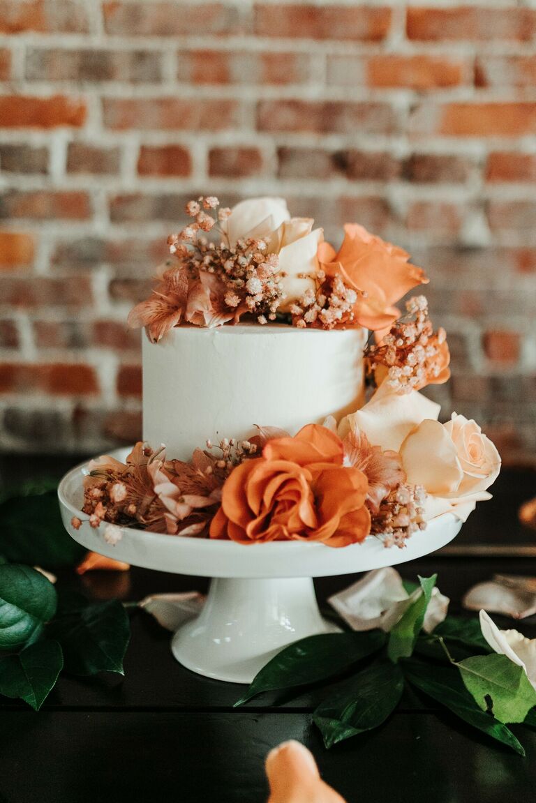 One-tier wedding cake with fresh orange flowers.