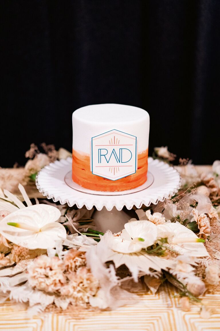 One-tier orange-and-white cake with modern monogram