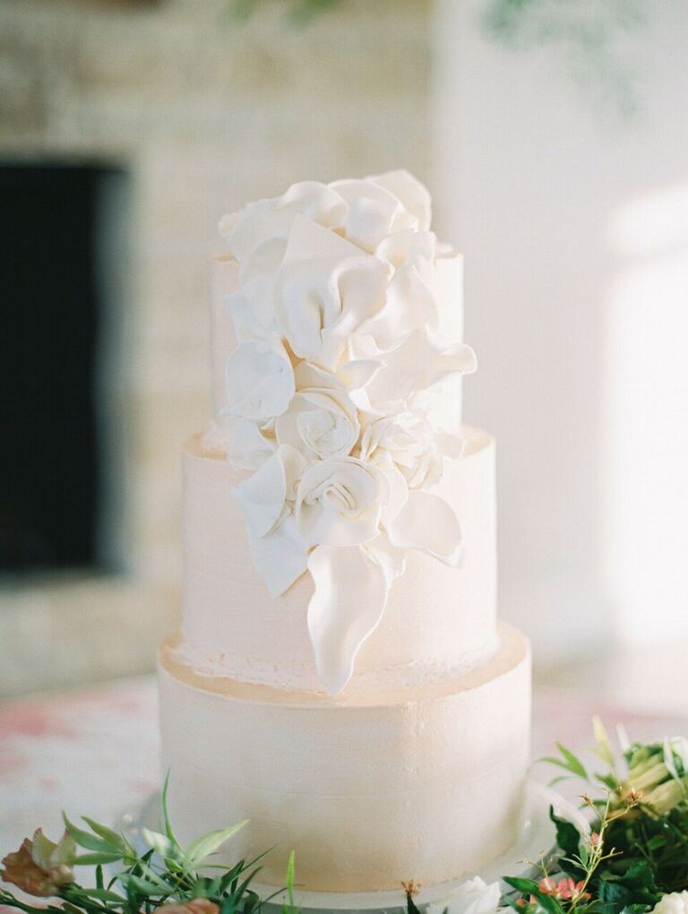 White three-tier wedding cake with white flower decorations