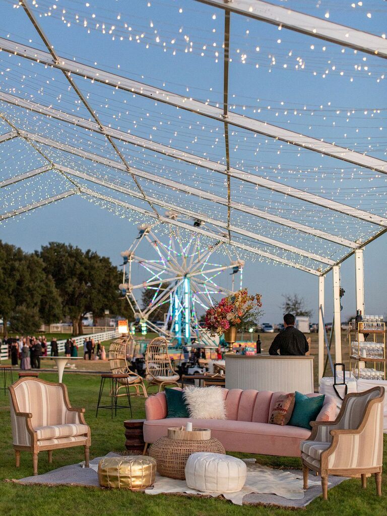 Lounge seating area at outdoor wedding reception with pink and neutral couches and chairs with throw pillows and textured poufs