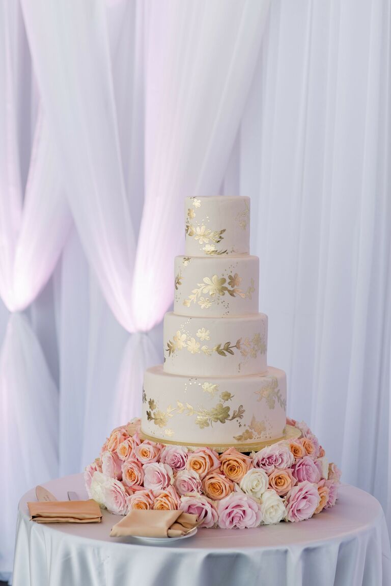 Gold-and-white wedding cake with fresh rose cake stand