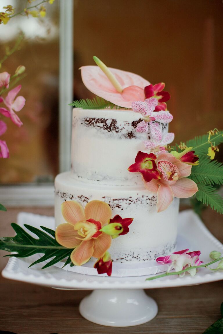 Semi-naked two-tier cake with tropical flower decorations