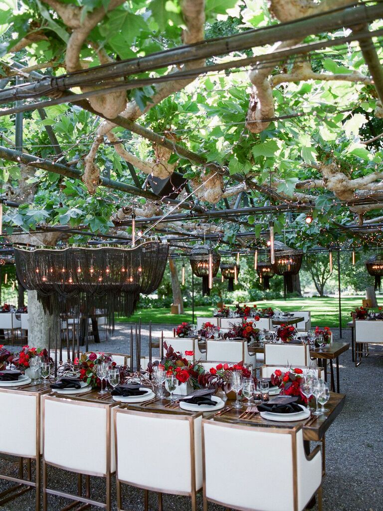 Outdoor modern wedding reception with lowered black macrame chandeliers and candles