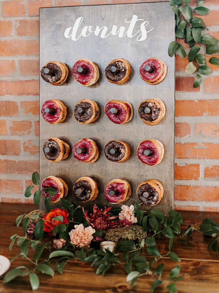 Donut wall with greenery accents at rustic wedding reception