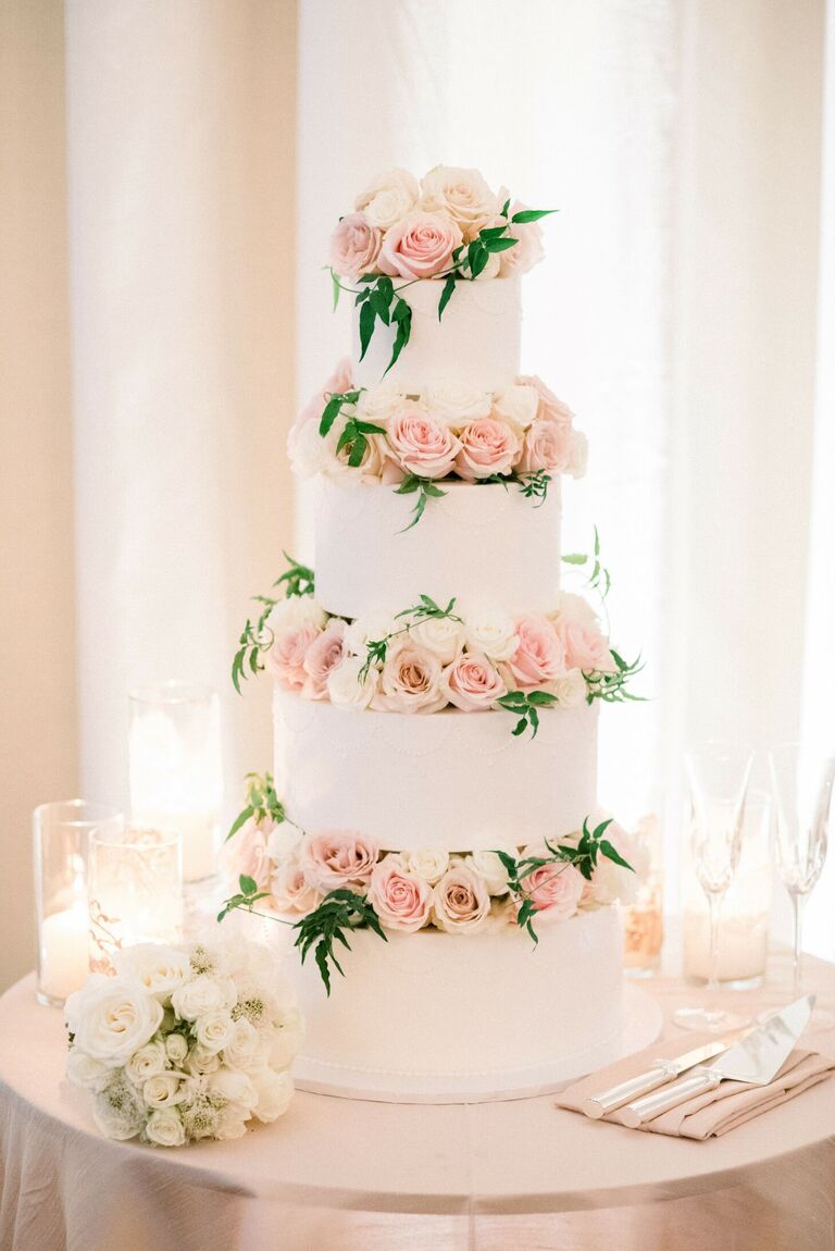 White four-tier cake with pink roses between each tier