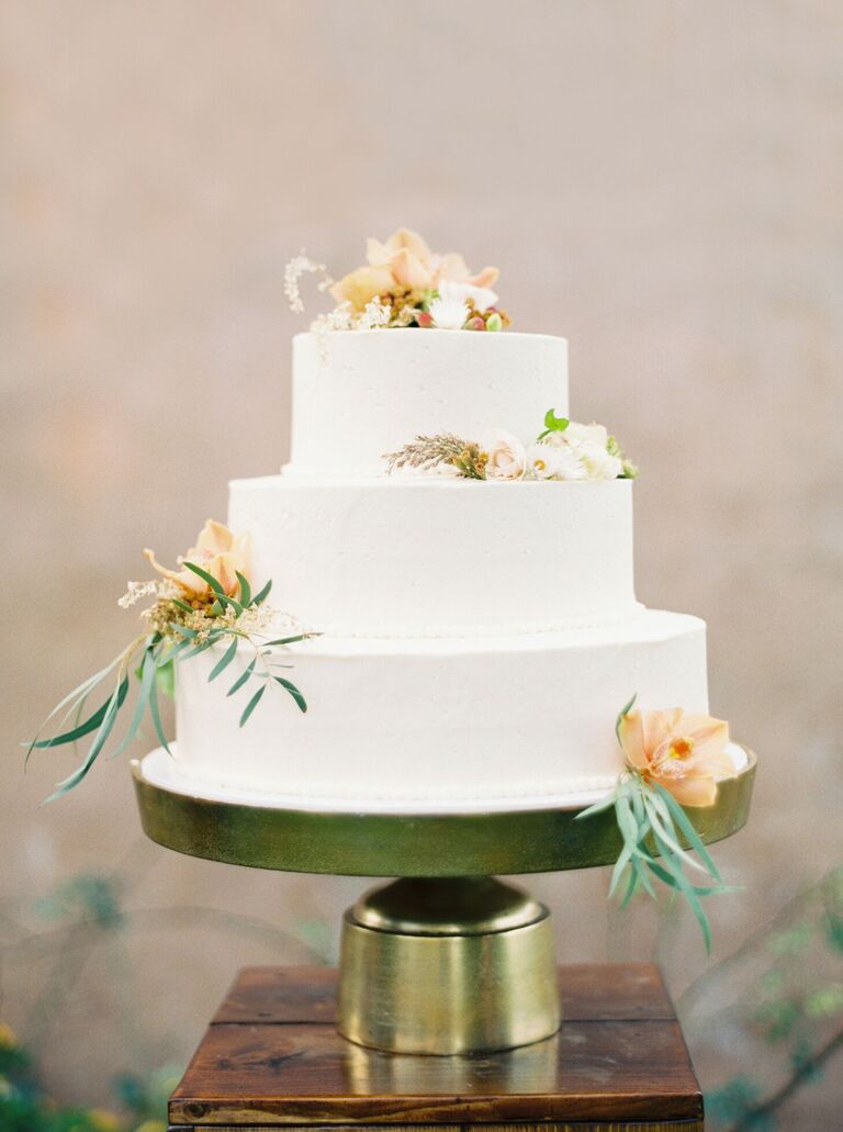 Minimal white three-tier wedding cake on gold cake stand